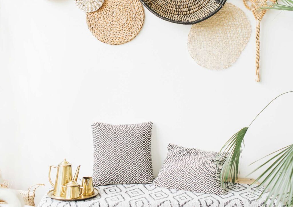 Woven wall baskets and gold tea set on patterned cushions — representing calm reflection and awareness of financial mindset.