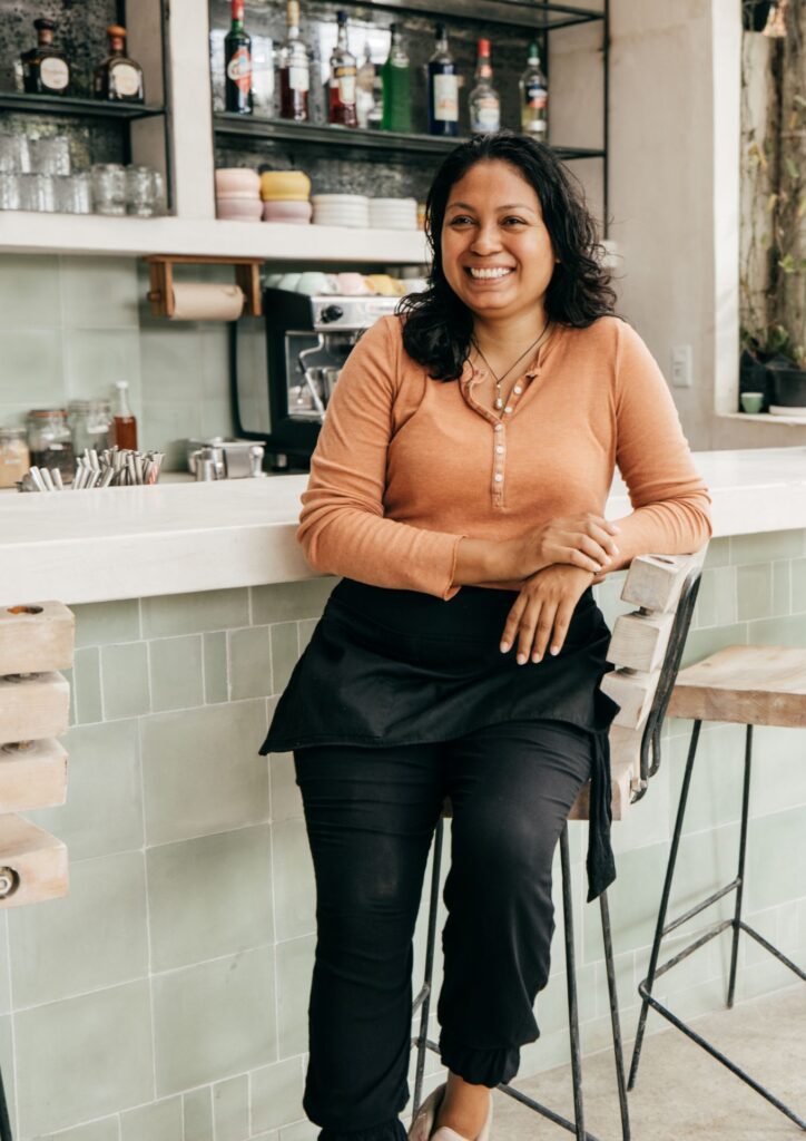 Woman smiling at cafe counter, representing Ikigai Wealth clients.