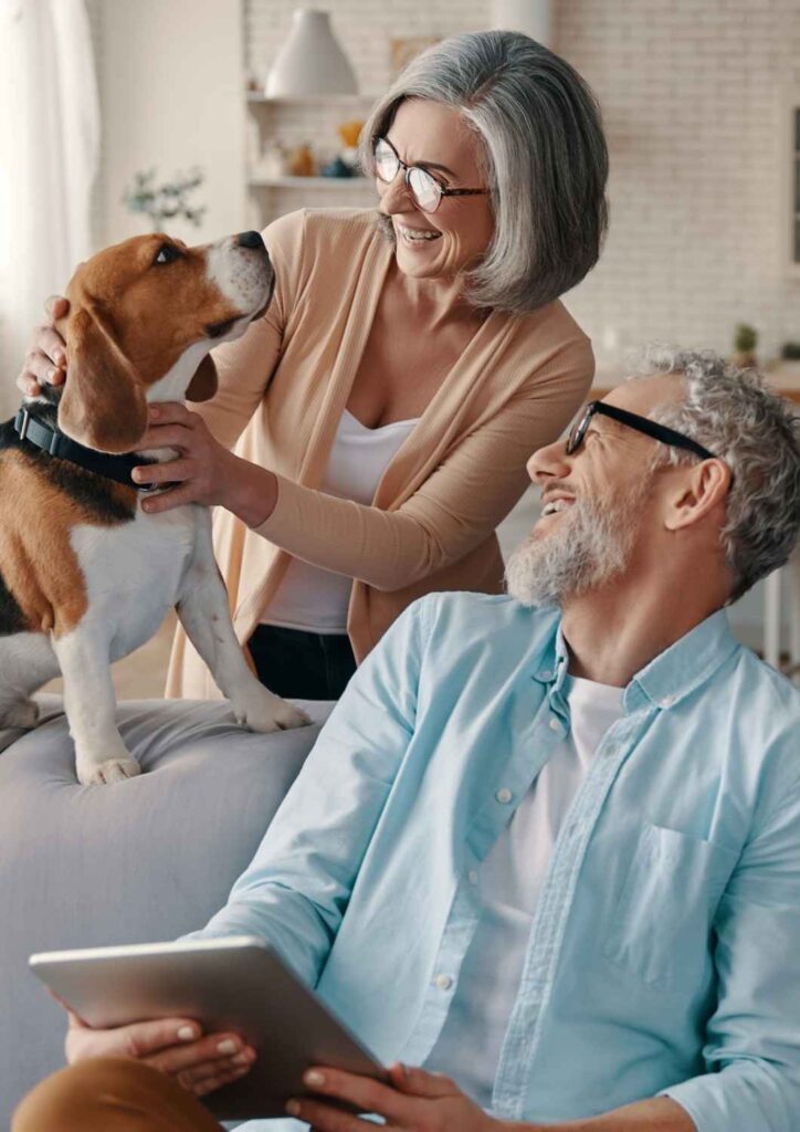Happy couple at home with their dog, symbolising financial freedom and peace of mind in retirement.