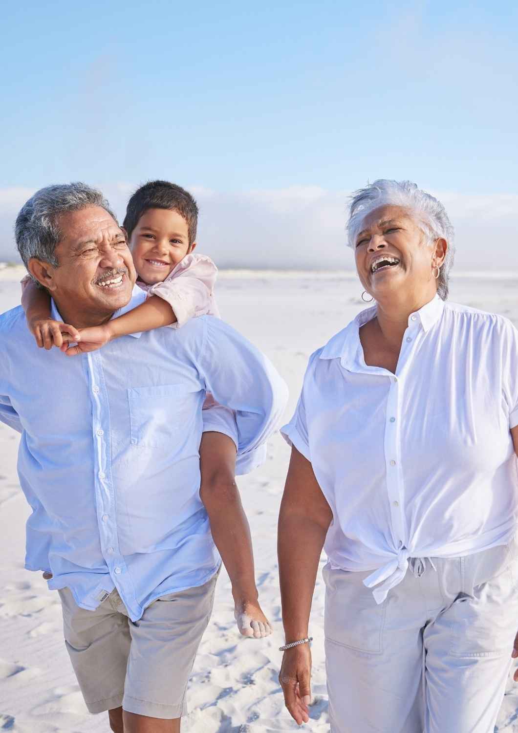 Retired couple walking on the beach with grandchild, enjoying financial freedom after retirement.