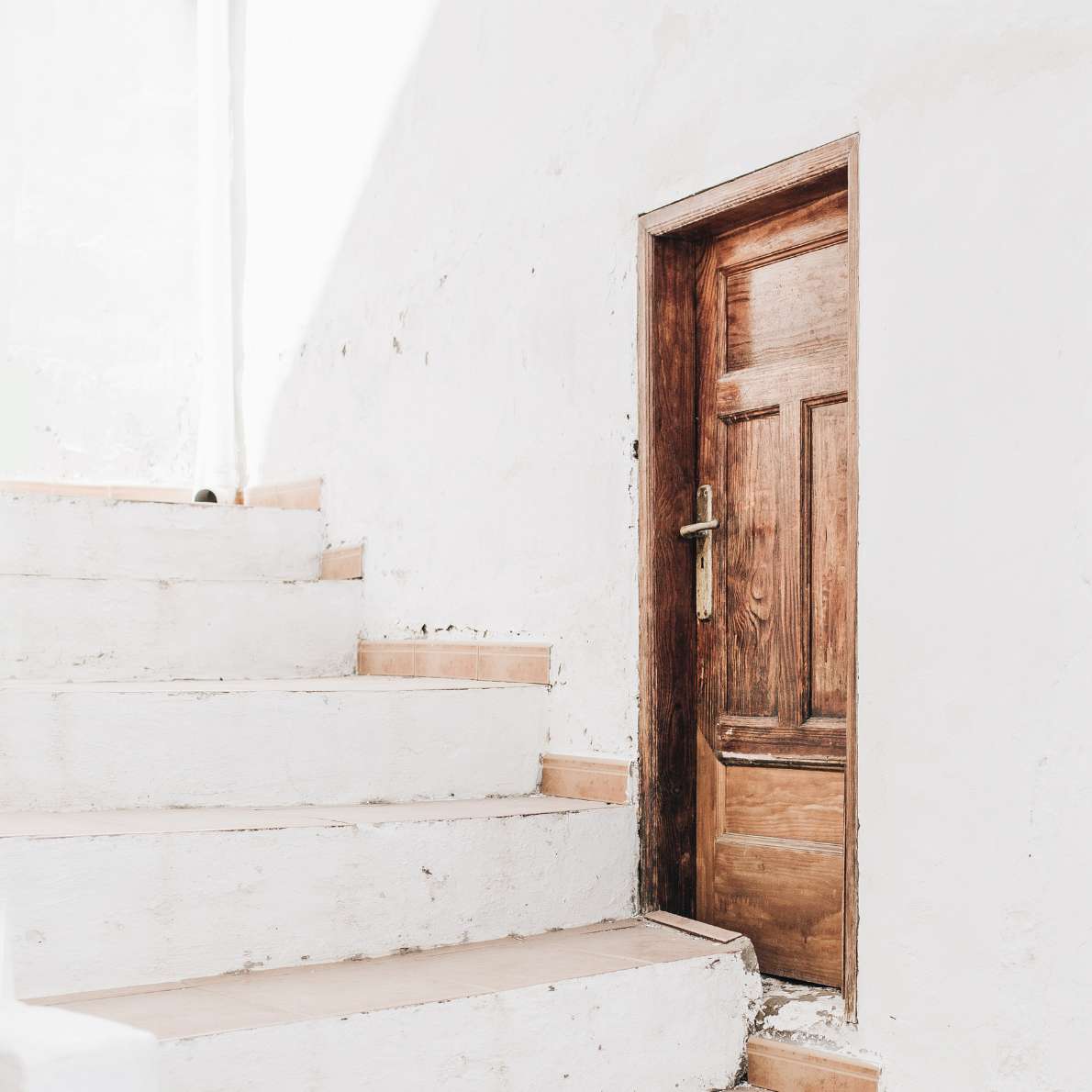 Whitewashed stairs and wooden door, representing new beginnings and guided financial discovery.