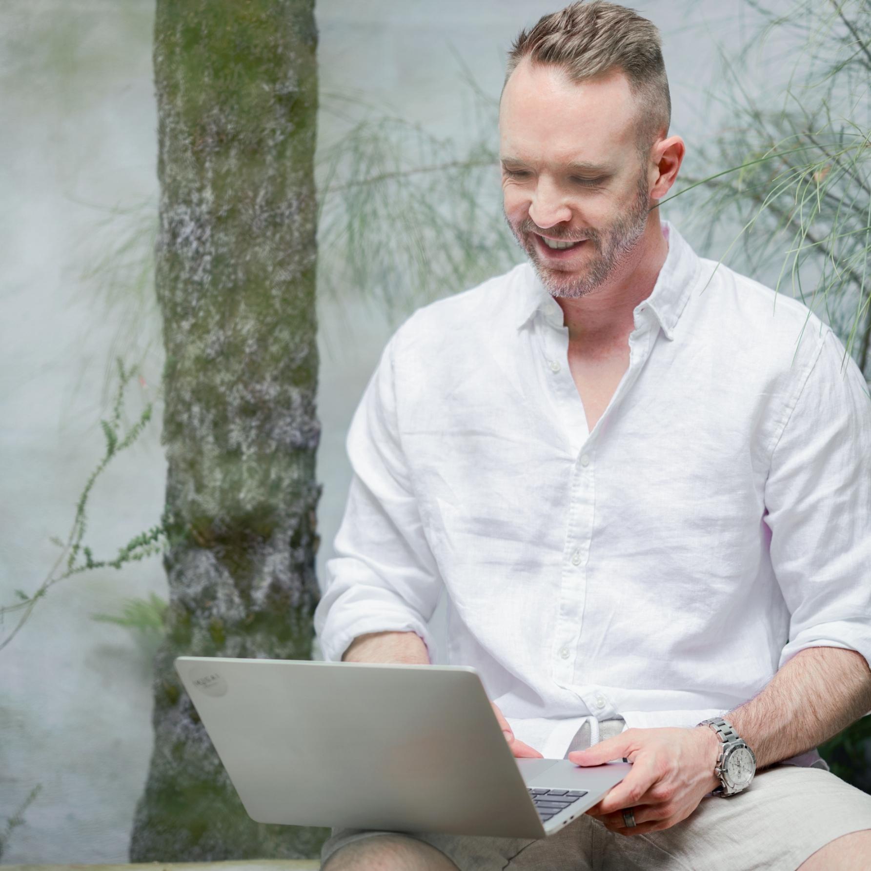 Devan from Ikigai Wealth smiling while working on a laptop, representing approachable, human-centred financial advice.