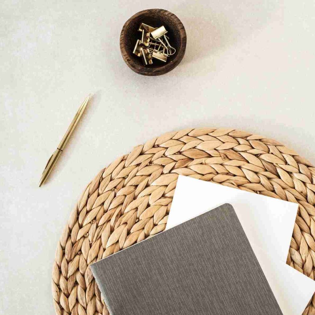 Notebook, pen, and woven mat — symbolising structure, planning, and intentional financial strategy.