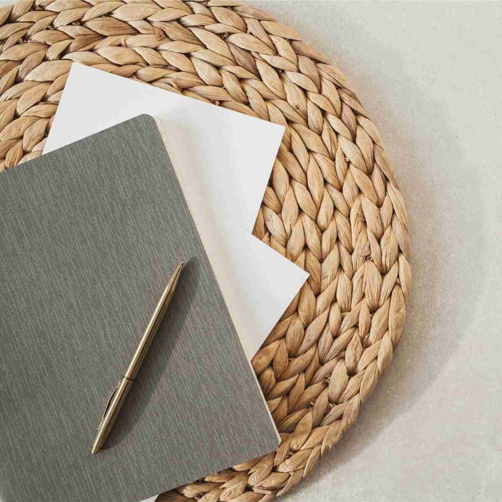 Notebook, pen, and woven mat, symbolising structure, planning, and intentional financial strategy.