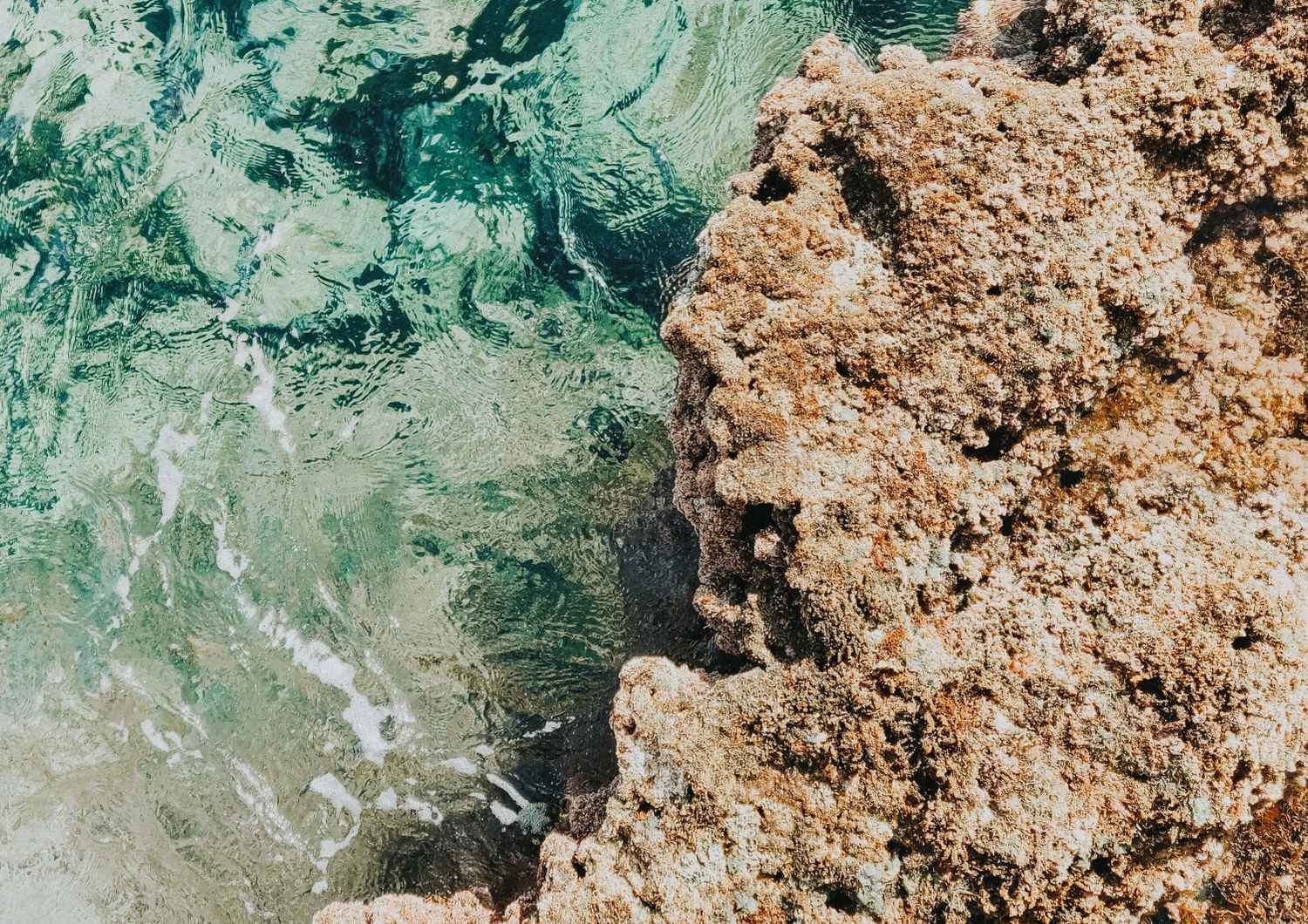 Close-up of clear ocean water meeting rugged rocks, symbolising clarity, stability, and balance in taking control of long-term financial planning.