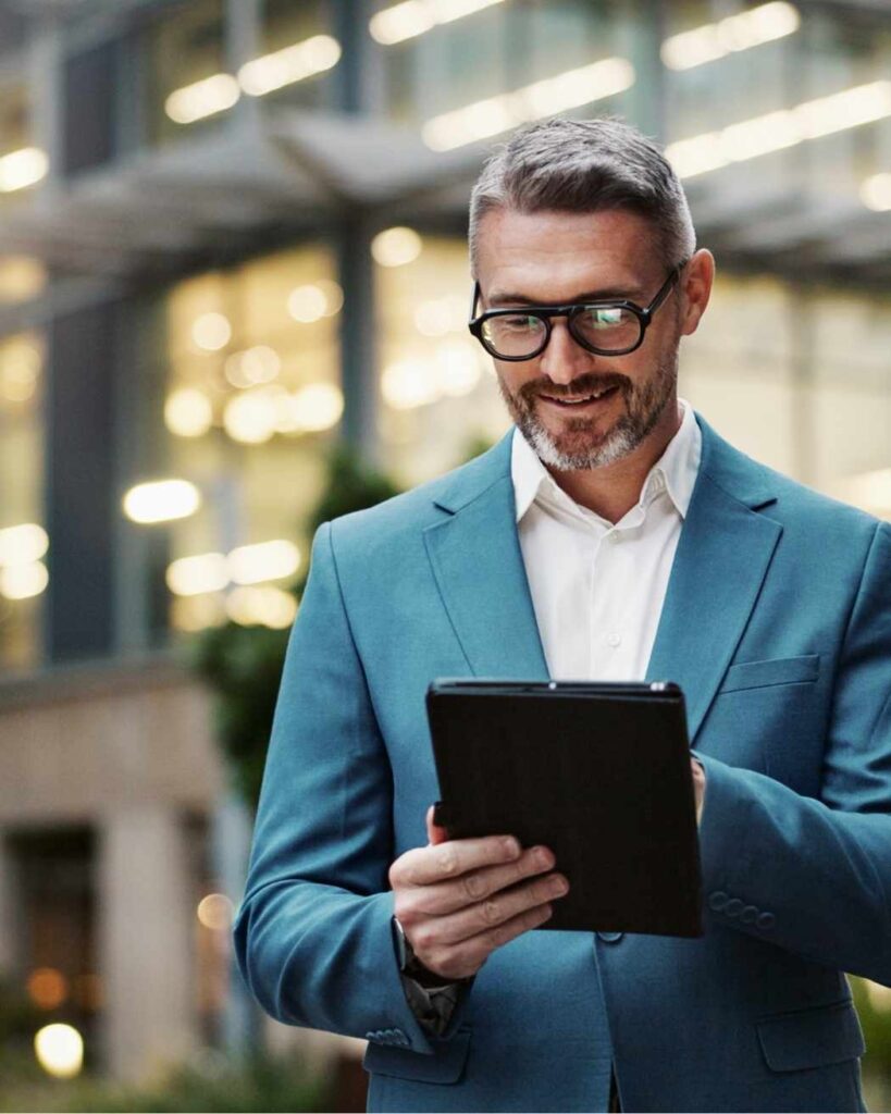 Professional man in a teal suit reviewing financial plans on a tablet, symbolising clarity, focus, and confident wealth strategy.