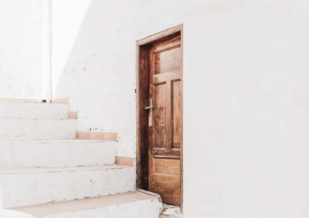 Whitewashed stairs and wooden door, representing steady progress and purposeful financial habits.