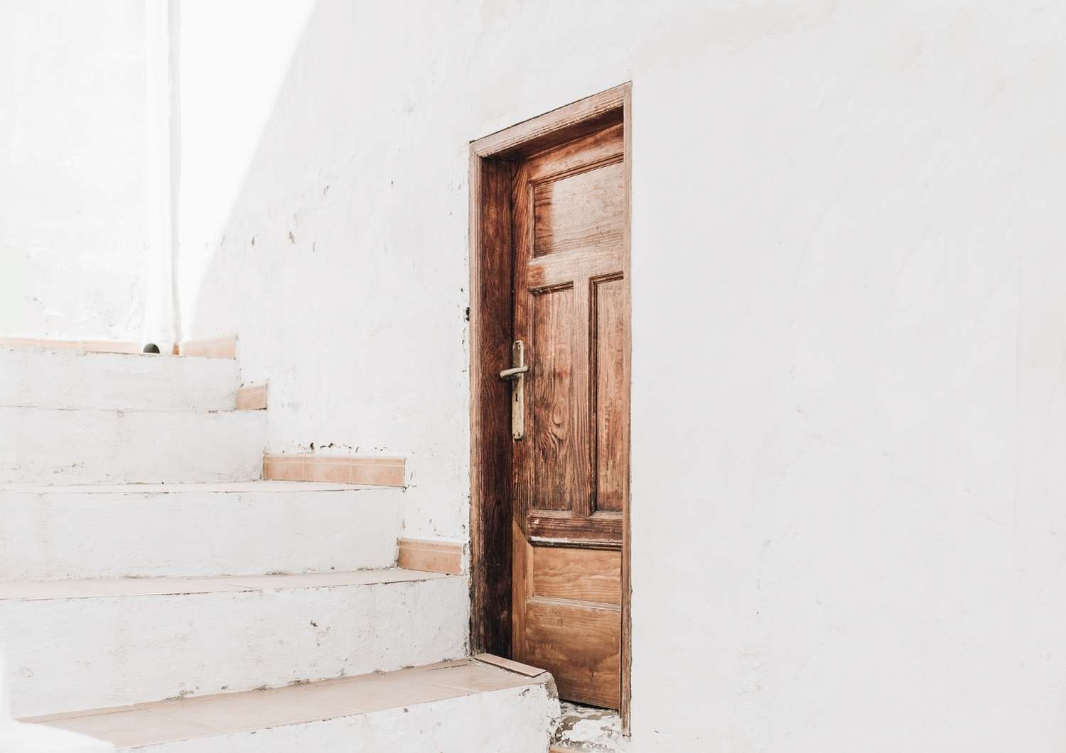 Whitewashed stairs and wooden door, representing steady progress and purposeful financial habits.