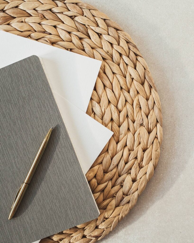 Notebook and pen on a woven table, representing financial freedom and intentional lifestyle planning.
